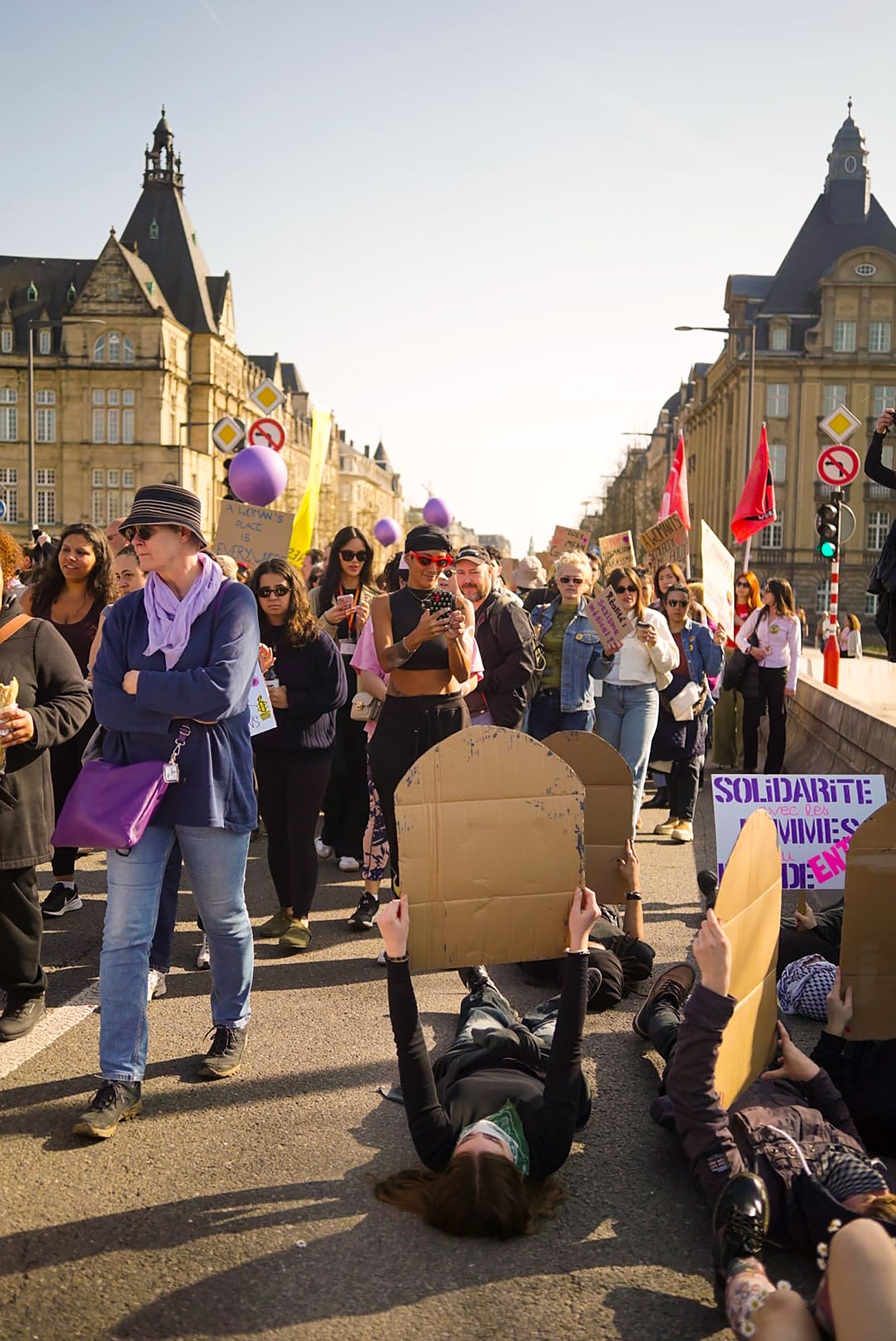 Picture of people lying on the ground holding up cardboard gravestones with statistics on violence against marginalised people.